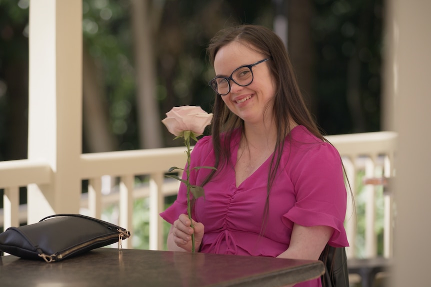 Olivia grins on a date, holding a large flower.