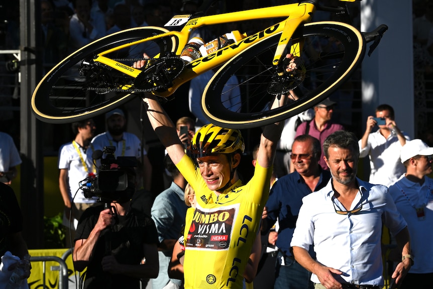 Jonas Vingegaard holds his bike aloft after claiming the Tour de France.