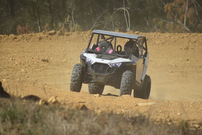 An year 8 year old girl drives a buggy fast on a dirt track