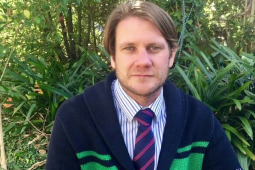 A man wearing a cardigan over a shirt and tie