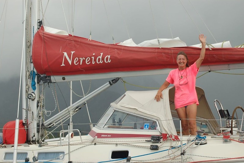 Une femme marin dans une chemise rose forme à bord d'un petit yacht. 