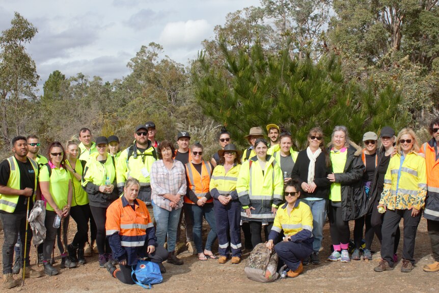 A group of about 30 in high-viz vests in the bush