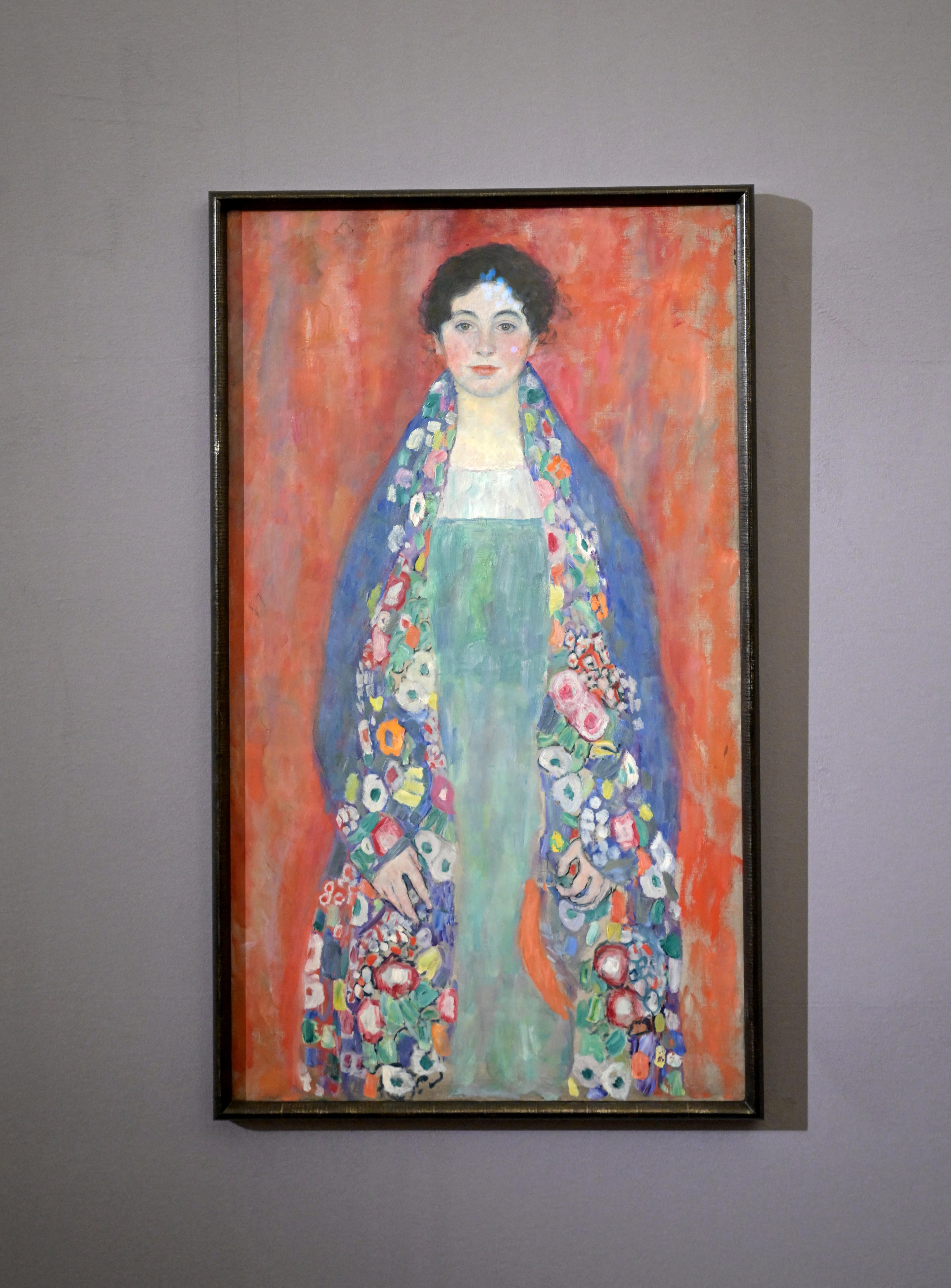 Photo of Klmt painting of woman wearing blue shawl on orange background 