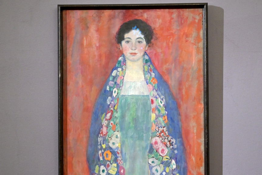 Photo of Klmt painting of woman wearing blue shawl on orange background 