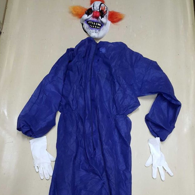 A clown costume - blue jumpsuit, mask and gloves, laid out flat.