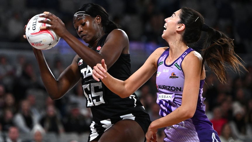 A Collingwood Magpies Syper Netball player beats a Queensland Firebirds opponent to the ball.