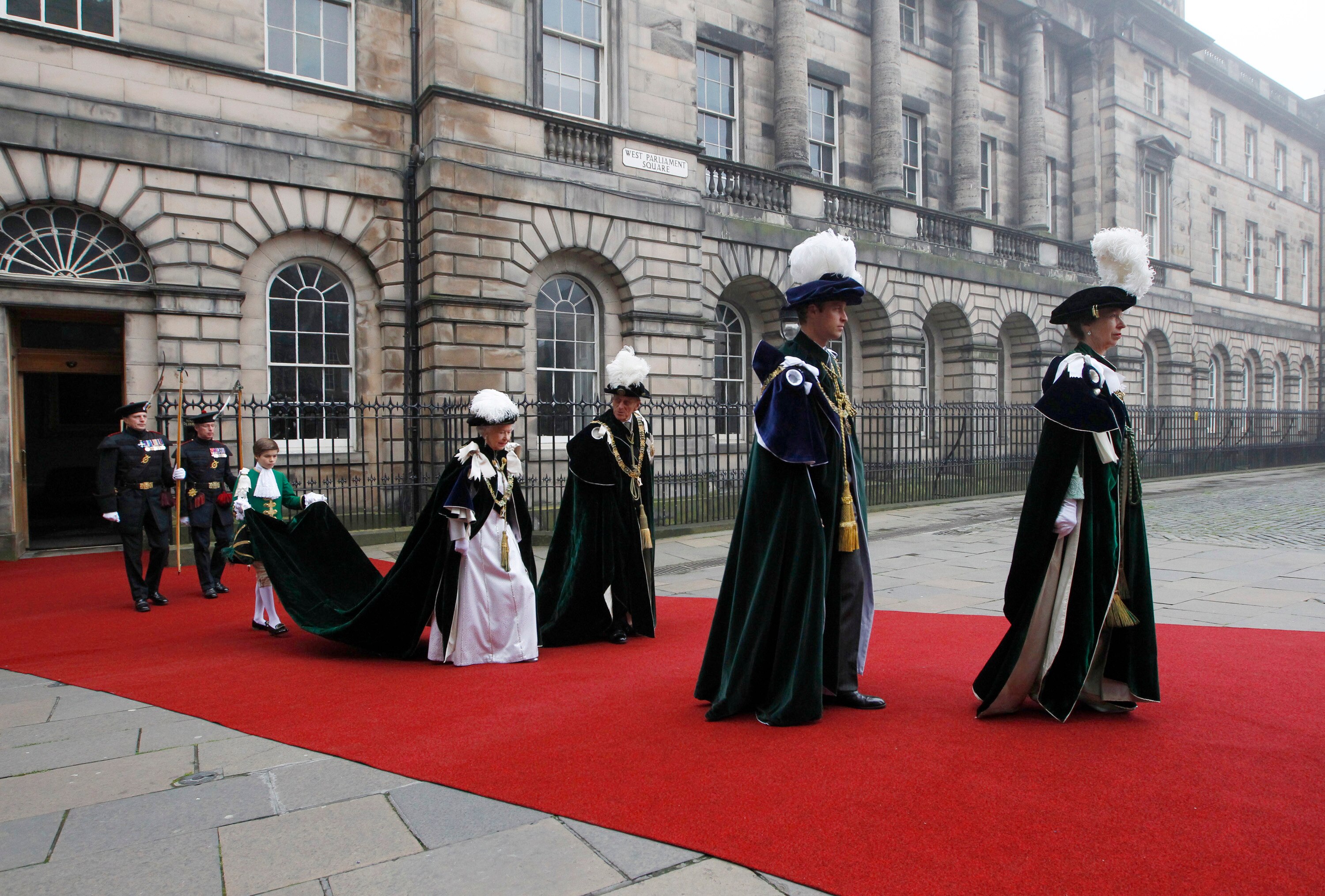 Britain's Prince William walks with Princess Anne, Queen Elizabeth and her husband Prince Phillip on a red carpet.