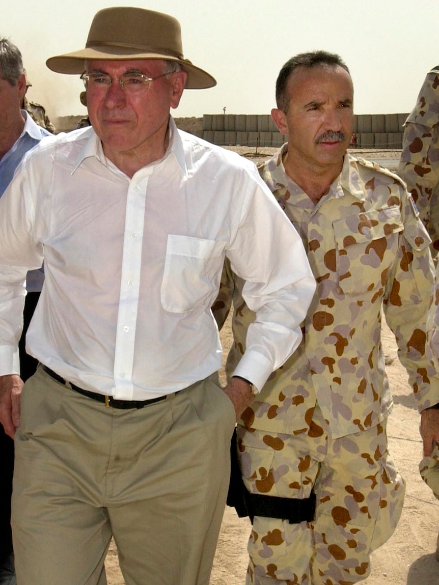 Andrew Nikolic, in army fatigues, walks beside Australian Prime Minister John Howard in Iraq in 2005.