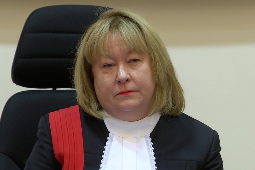 A woman with blonde hair wearing a black robe and white tie