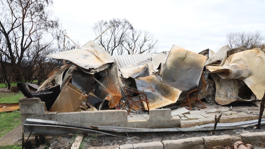 The fire blackened remains of a house sit crumpled together.