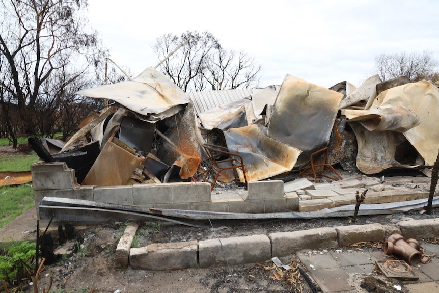 The fire blackened remains of a house sit crumpled together.