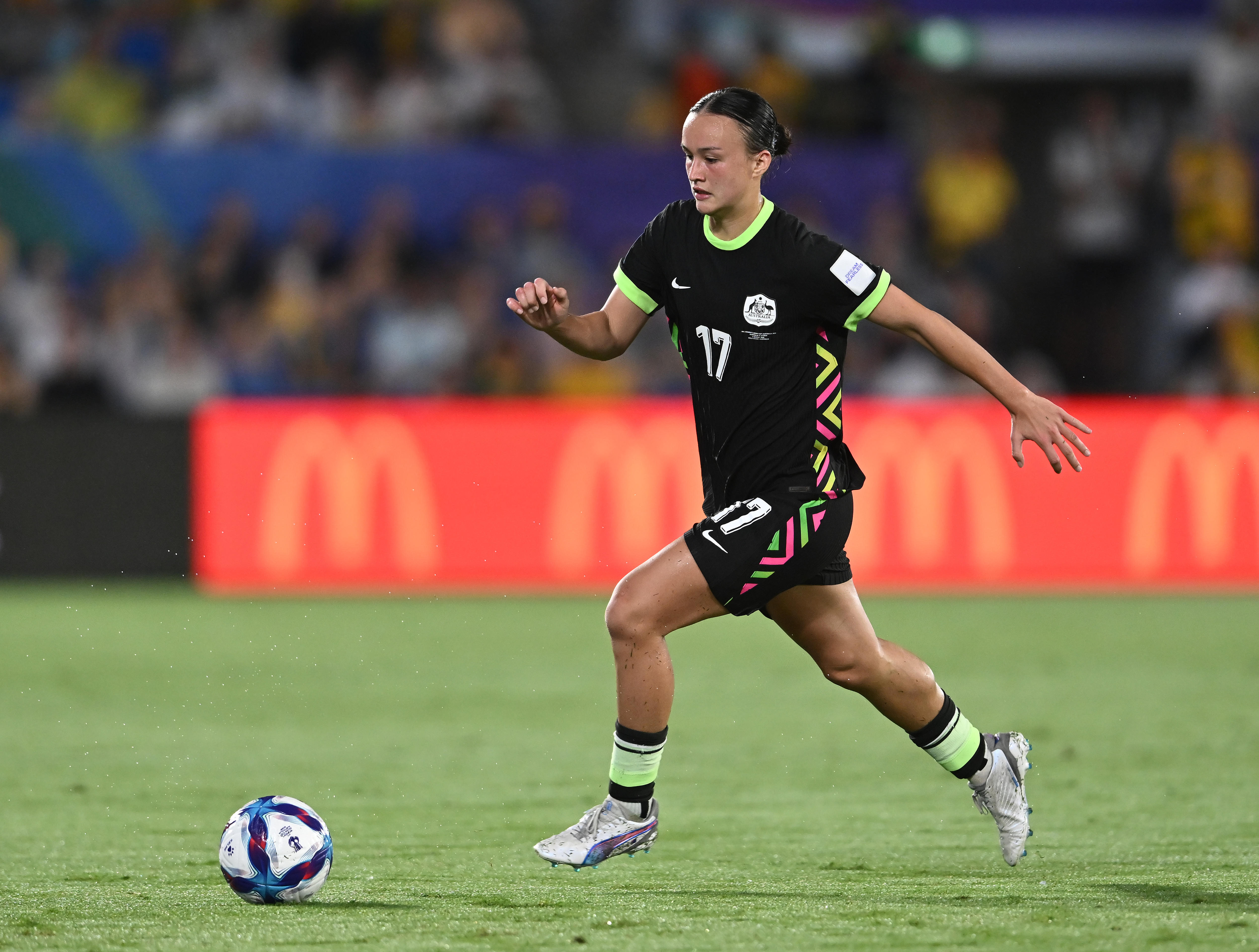 A soccer player in dark green runs with the ball