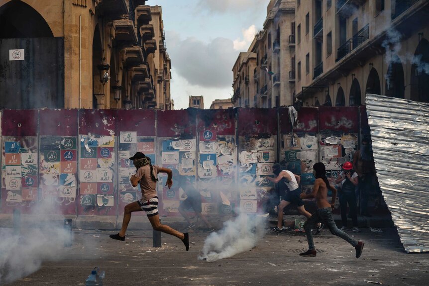 Demonstrators run from tear gas fired by police near the parliament building in Beirut.