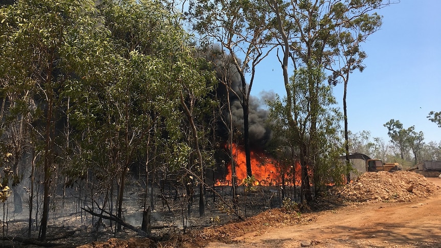A spot fire is seen burning along a property line as smoke billows in to the sky in the Darwin rural area.