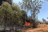 A spot fire is seen burning along a property line as smoke billows in to the sky in the Darwin rural area.