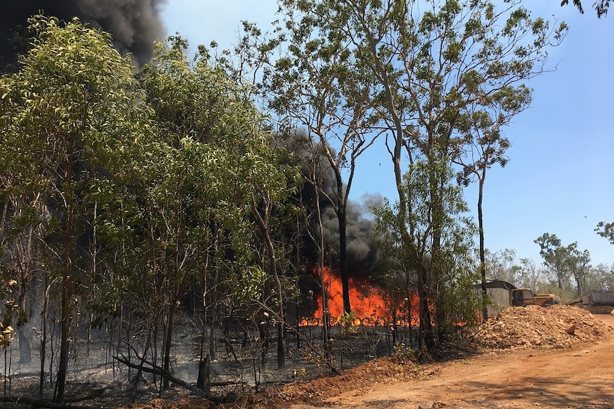 A spot fire is seen burning along a property line as smoke billows in to the sky in the Darwin rural area.