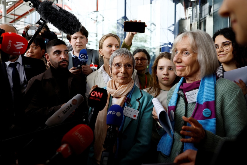 Smiling women front a media pack after their human rights court win