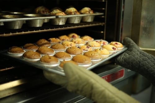 a tray of muffins being taken out of a large oven