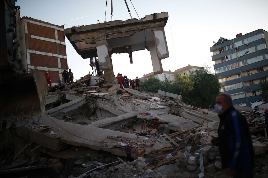 Members of rescue services search for survivors in the debris of a collapsed building.