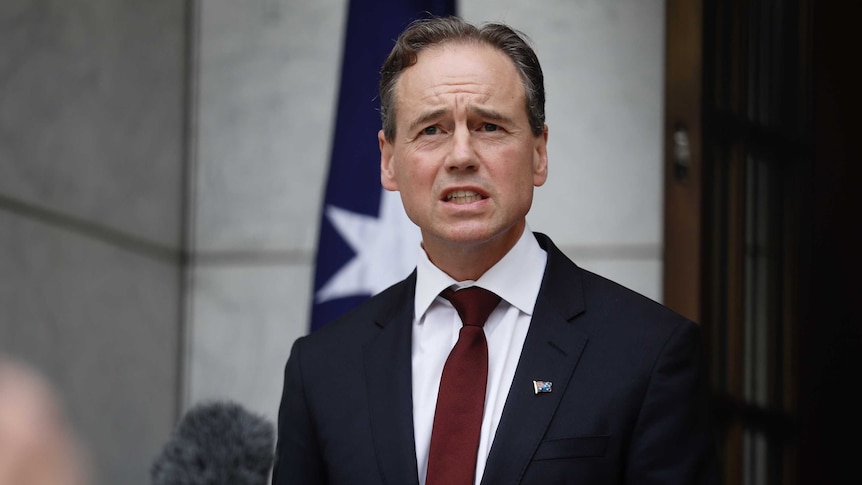 Hunt mid-shot, standing behind podium, wearing Australia flag pin on his suit lapel.