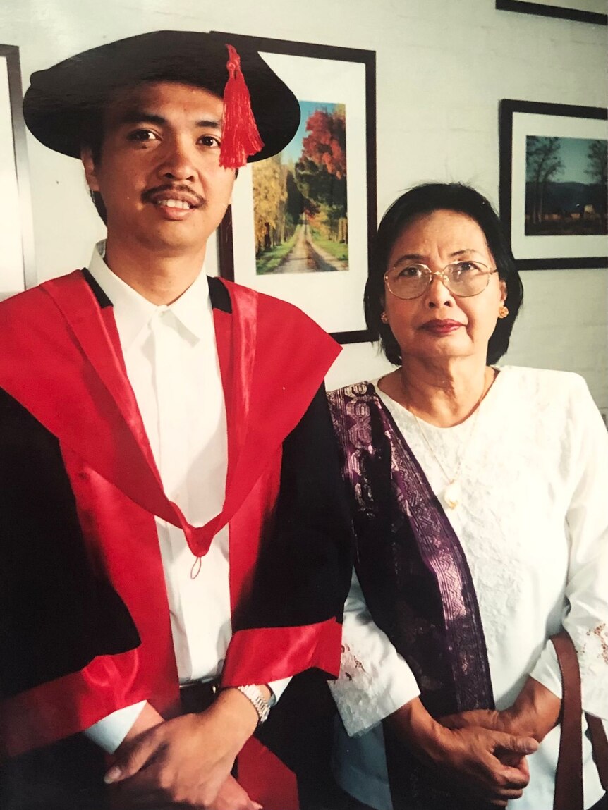 Putu Pendit wearing graduate rob with his mum