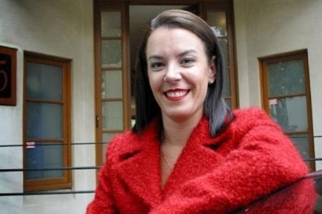 Une femme sourit à la caméra dans une veste rouge.