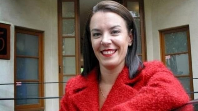 A woman smiles at the camera in a red jacket.