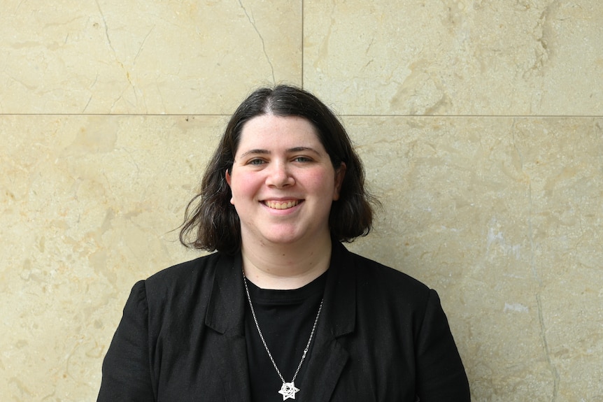 Shoshana is pictured wearing a black shirt, and she has the star of David necklace around her neck.