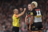 An NRL referee crosses his arms to signal to a Penrith player that he has been reported for a shoulder charge in a final.