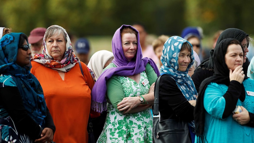 Five women stand in a park wearing brightly coloured headscarves.