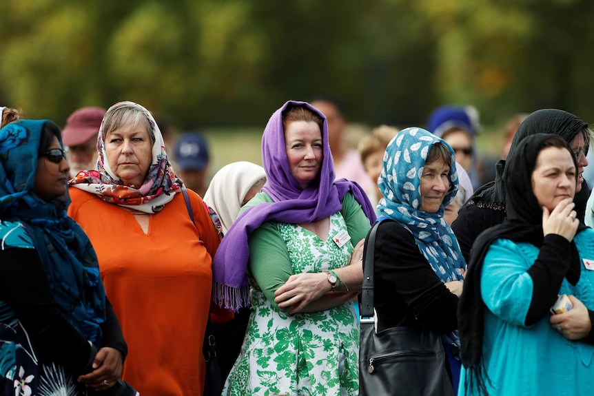 Five women stand in a park wearing brightly coloured headscarves.