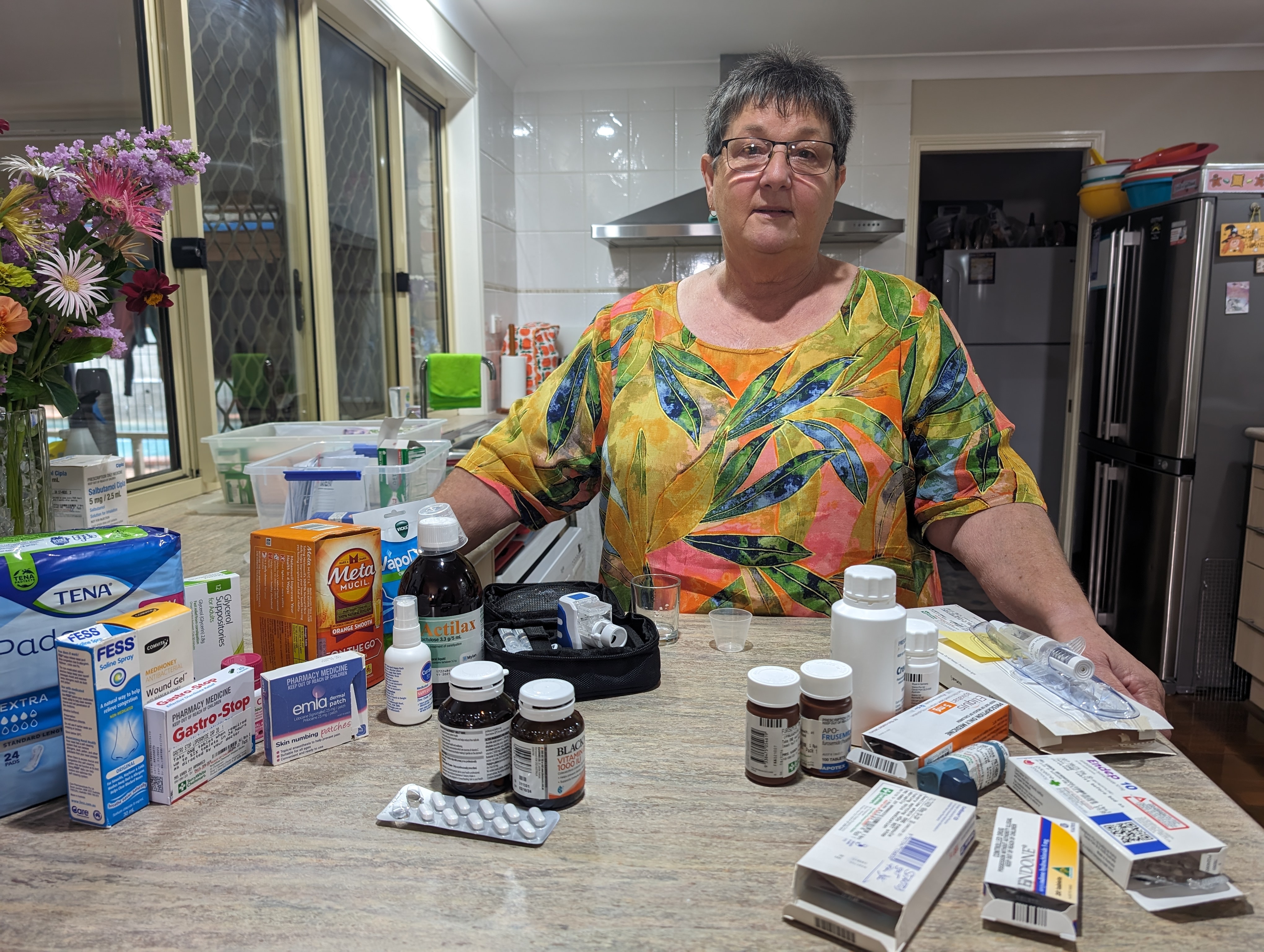 Karen Armanasco stands behind a counter laden with medications and over-the-counter pharmacy products.