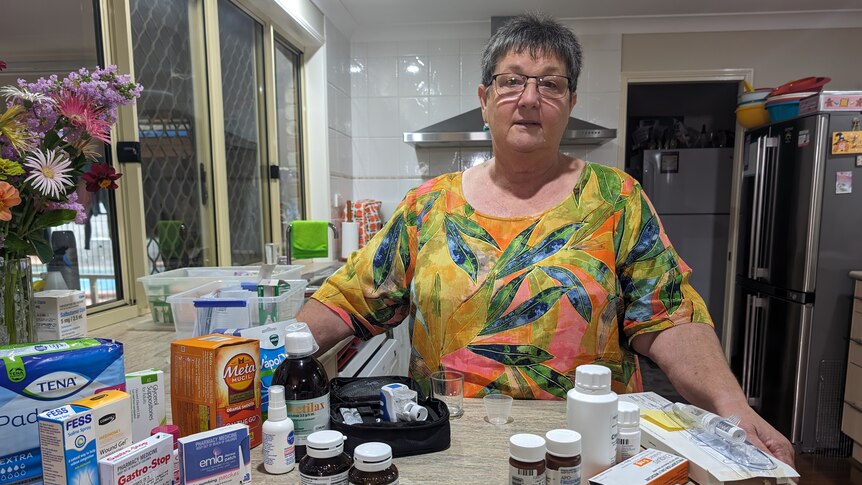 Karen Armanasco stands behind a counter laden with medications and over-the-counter pharmacy products.