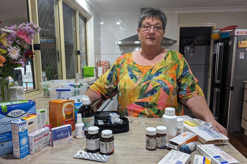 Karen Armanasco stands behind a counter laden with medications and over-the-counter pharmacy products.
