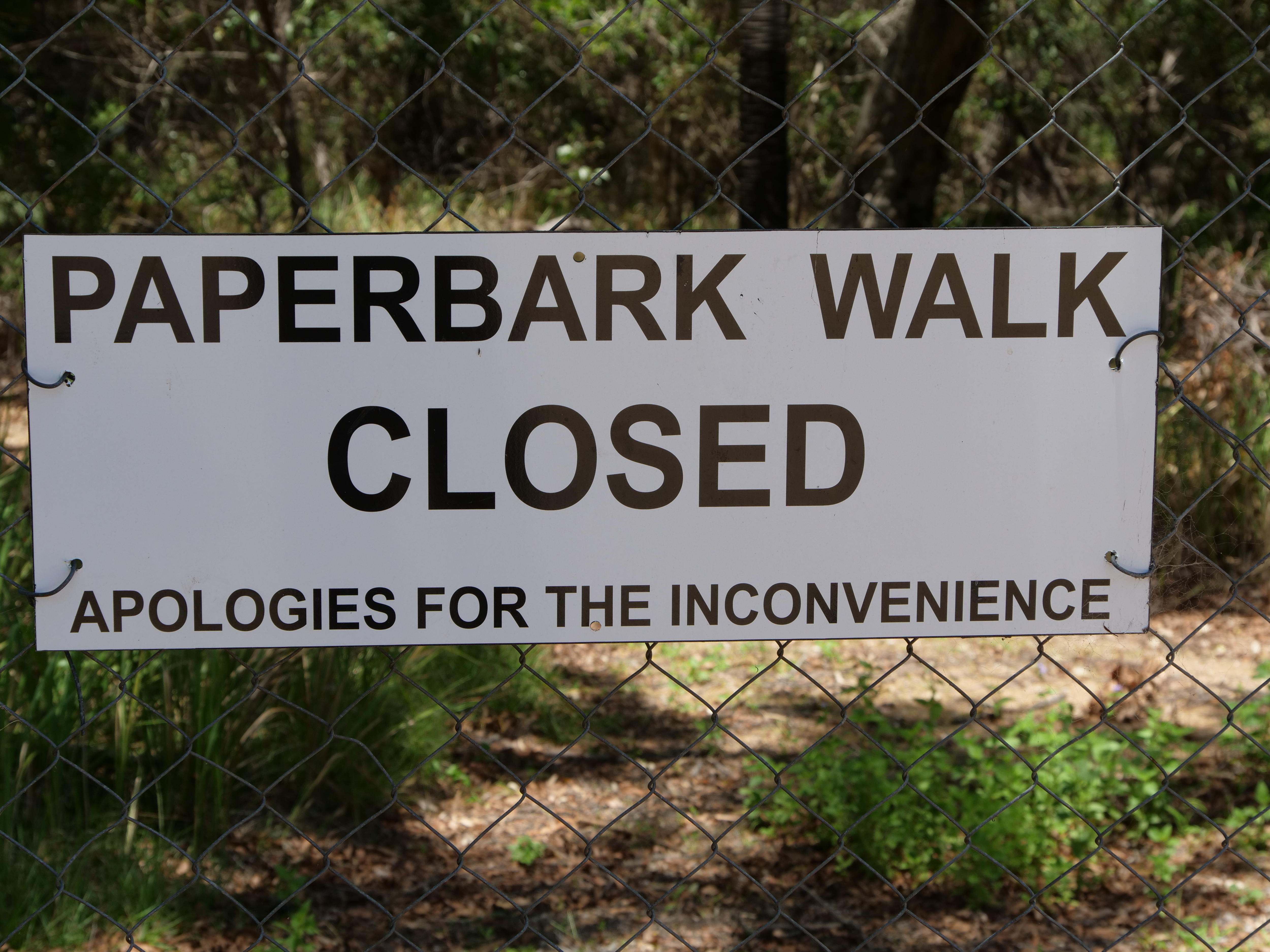 Un cartel en una valla que dice: "El paseo Paperbark está cerrado, disculpe las molestias."