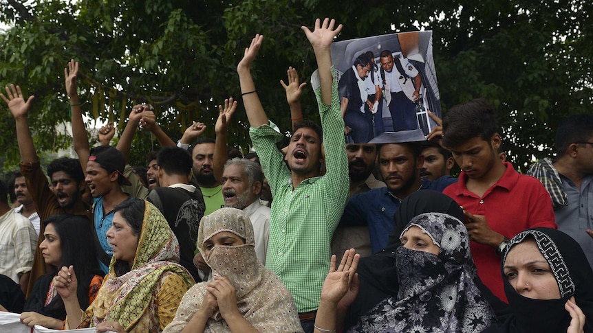 Relatives and area residents carry photographs of Zulfiqar Ali