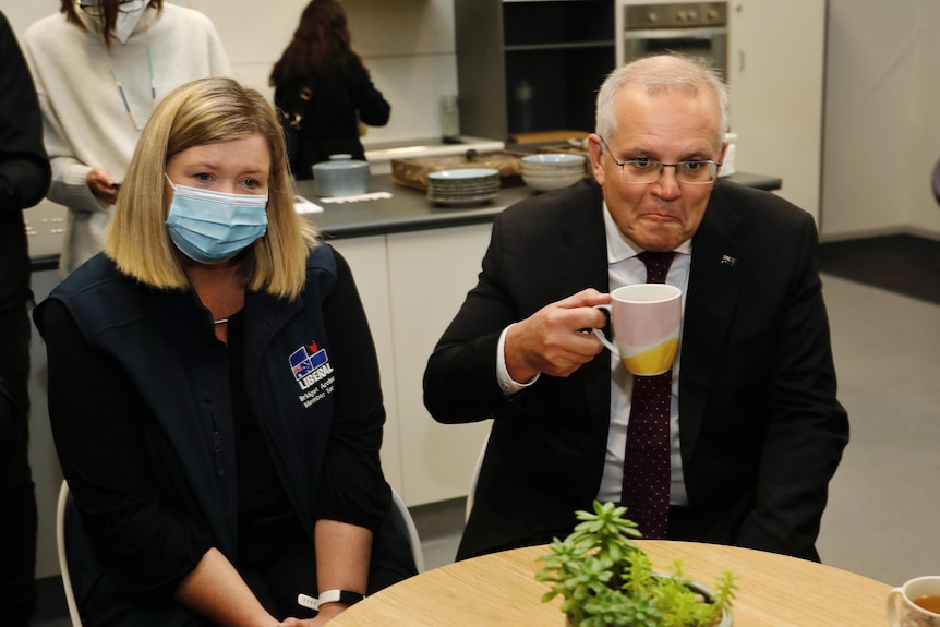 A woman in a face mask looks downcast while a man with a mug puckers his lips