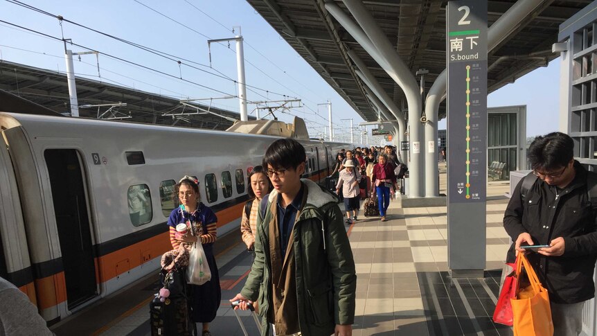 Young people board a train in Taiwan on a sunny day