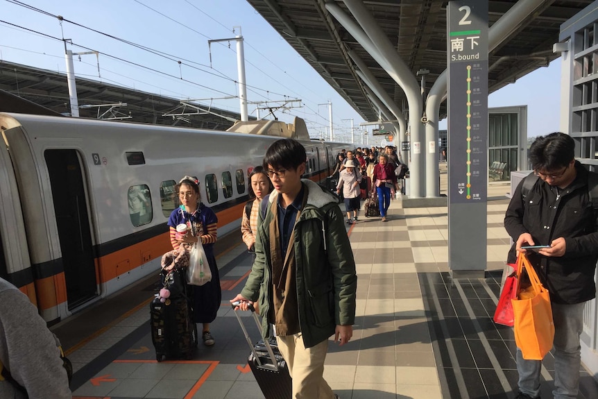 Young people board a train in Taiwan on a sunny day