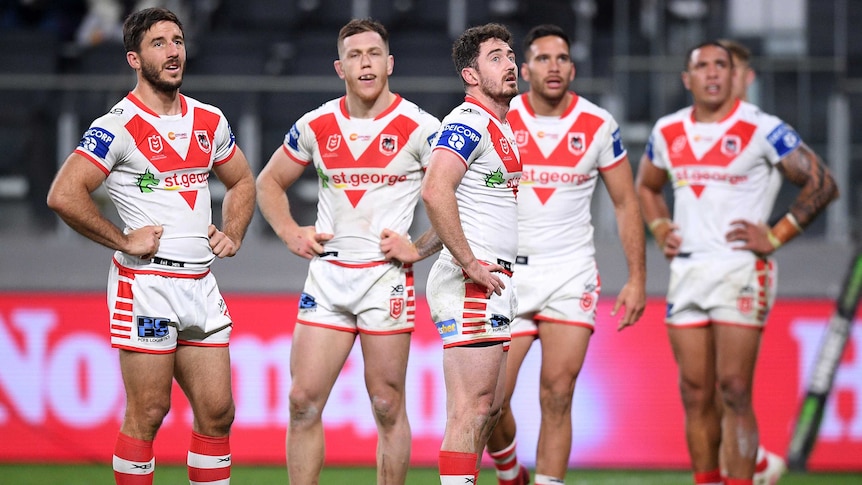 Dragons players look up off camera, standing with their arms on their hips