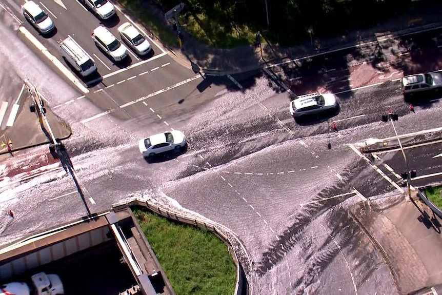 cars drive across a road flooded with water