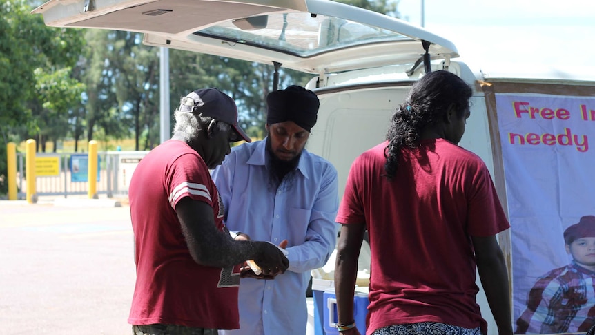 A man hands out a plastic container of food to another man.