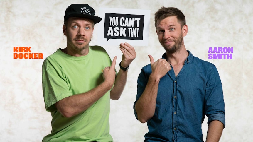 You Can't Ask That producers/directors Kirk Docker and Aaron Smith hold and point to the show's logo on set.