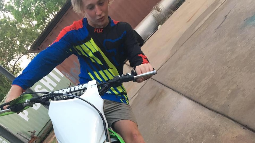A teenage boy on a tilting dirtbike
