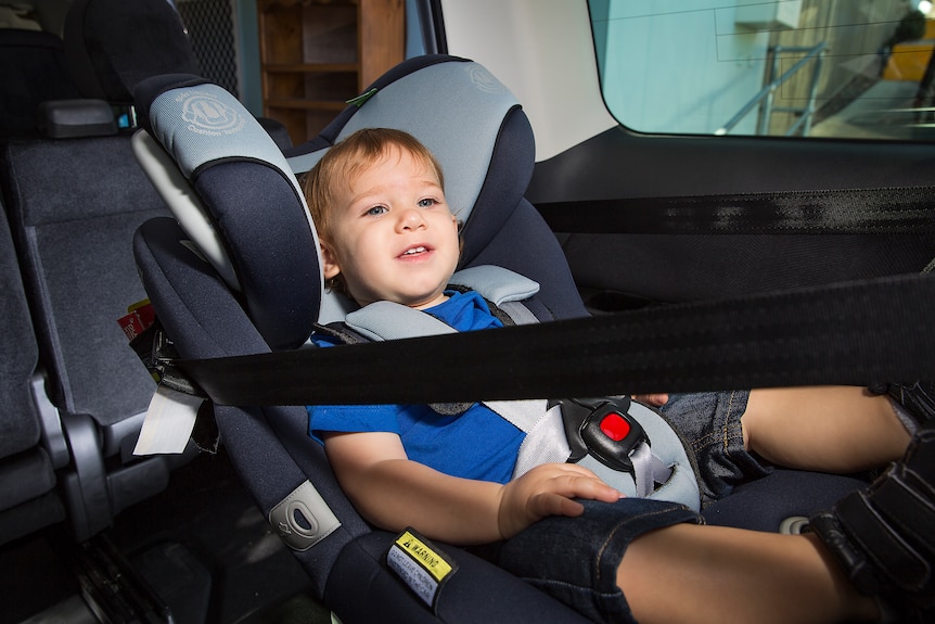 A child sits in a rear-facing car seat. 