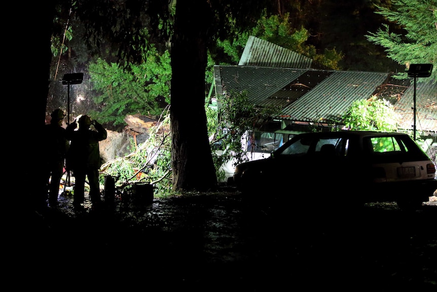 CFA firefighters look at a smashed house following fierce storms in Melbourne