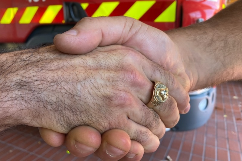 A close-up of two hands shaking, including one with a gold ring.