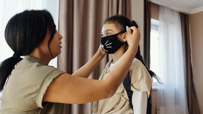 A woman puts a mask on her child