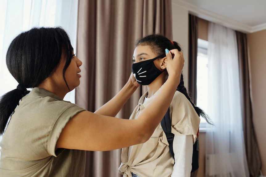 A woman puts a mask on her child