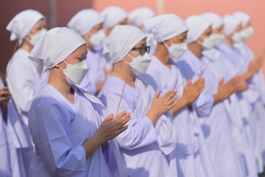 Women in white gowns holding incense.